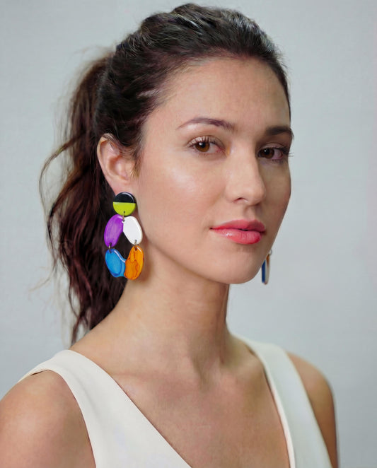 Woman wearing colorful earrings against a plain background