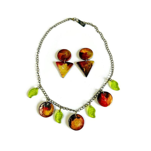 Necklace with clay and leaf charms on a white background with matching earrings