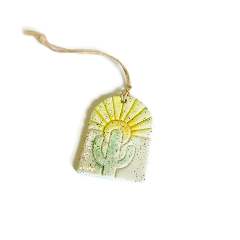 Decorative tag with a cactus design and sunburst on a white background
