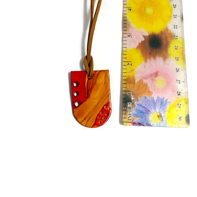 Colorful pendant next to a floral-patterned ruler on a white background
