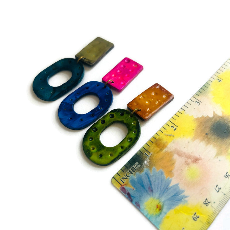 Colorful clay statement hoops with a floral-patterned ruler for scale on a white background