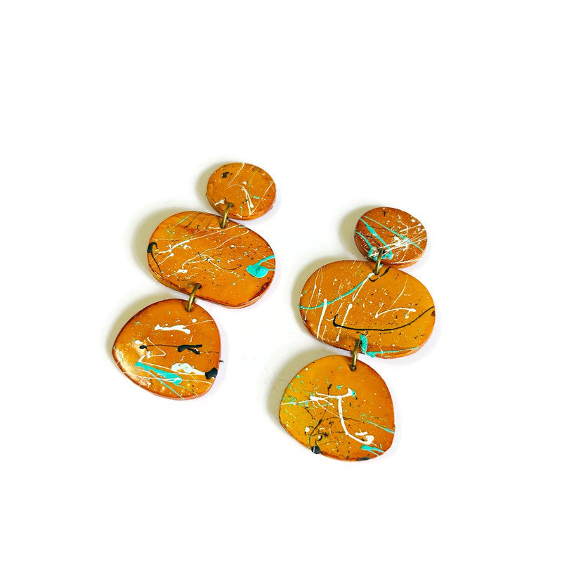 Pair of mustard yellow earrings with marbled design on a white background