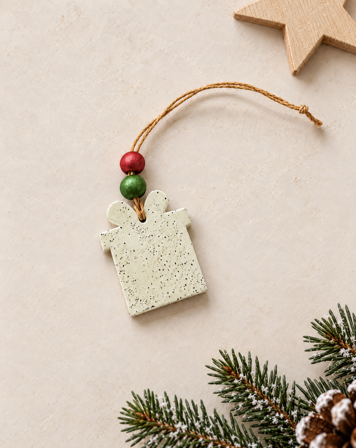 Clay square ornament with speckled surface and red/green beads, tan hanging cord