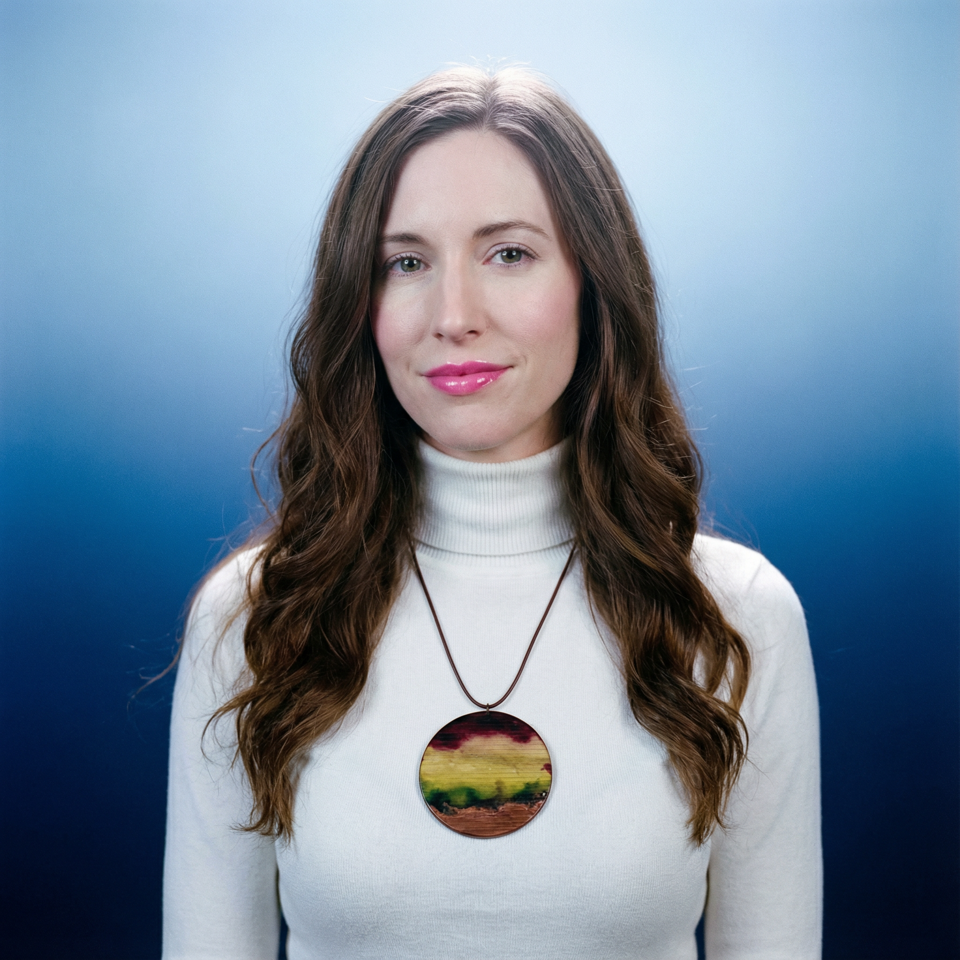 Woman wearing a white turtleneck sweater with a colorful necklace against a blue background
