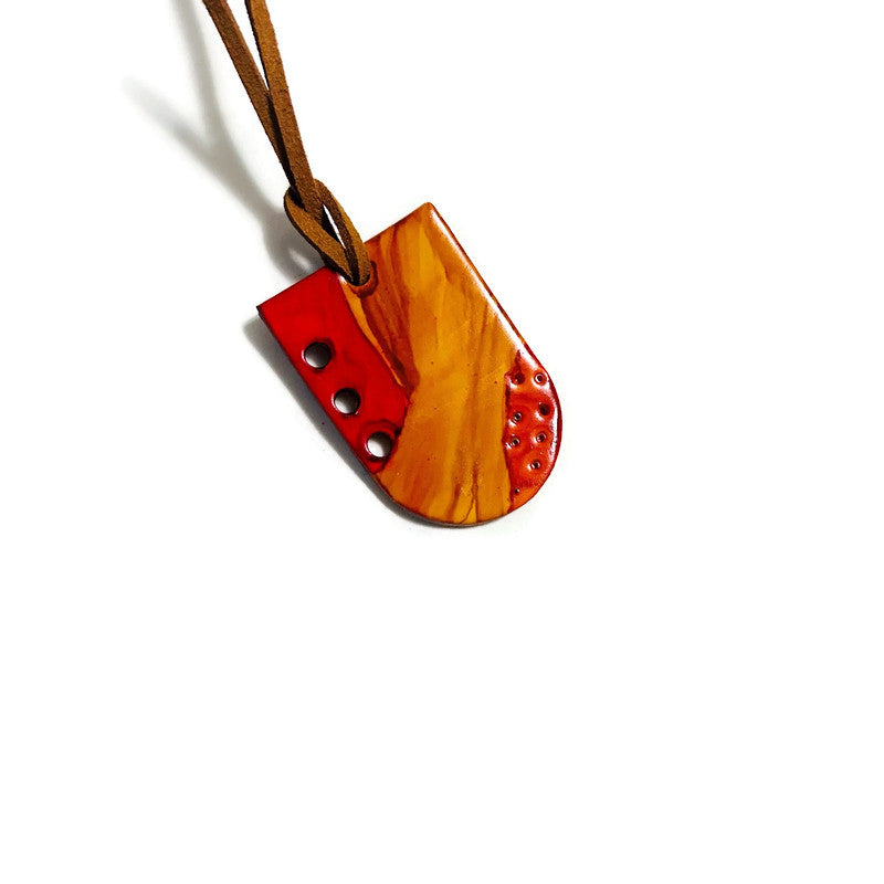  Clay pendant with red accents on a white background