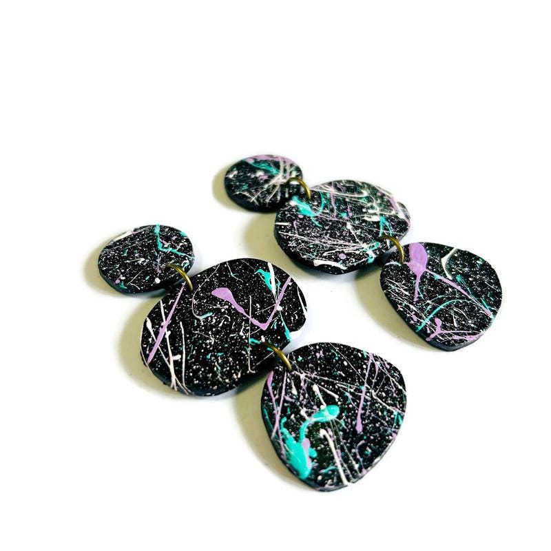 Black earrings with colorful splashes on a white background