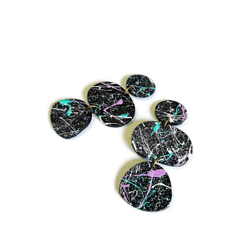 Set of black painted splashed earrings on a white background