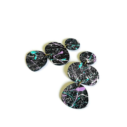 Set of black painted splashed earrings on a white background