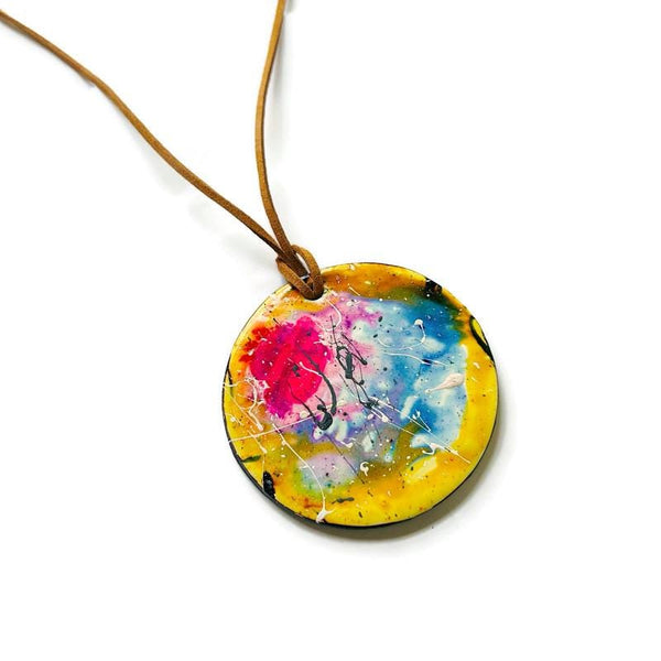 Colorful round pendant on a brown cord against a white background