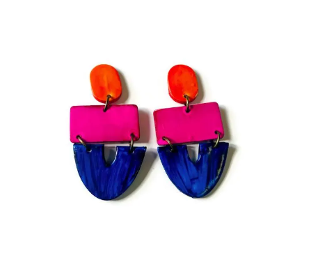 Colorful earrings with pink, orange, and blue geometric design on a white background