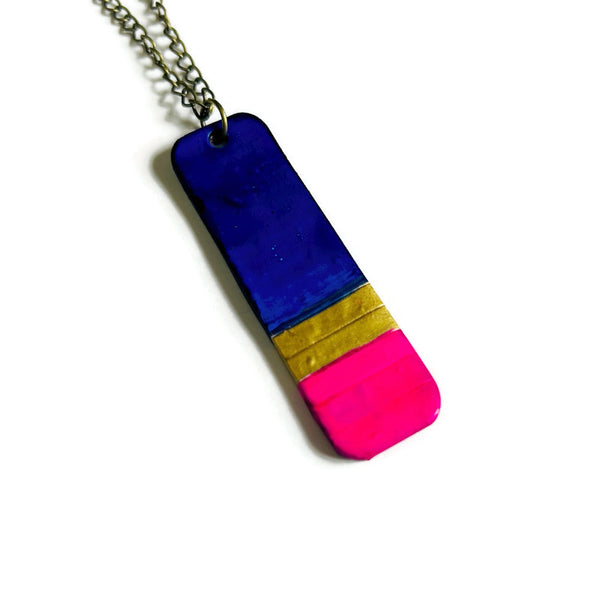 Colorful pendant necklace with blue, gold, and pink sections on a white background