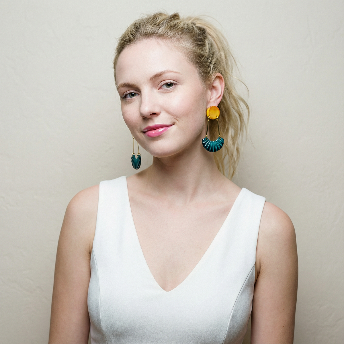 Woman wearing colorful earrings against a plain background