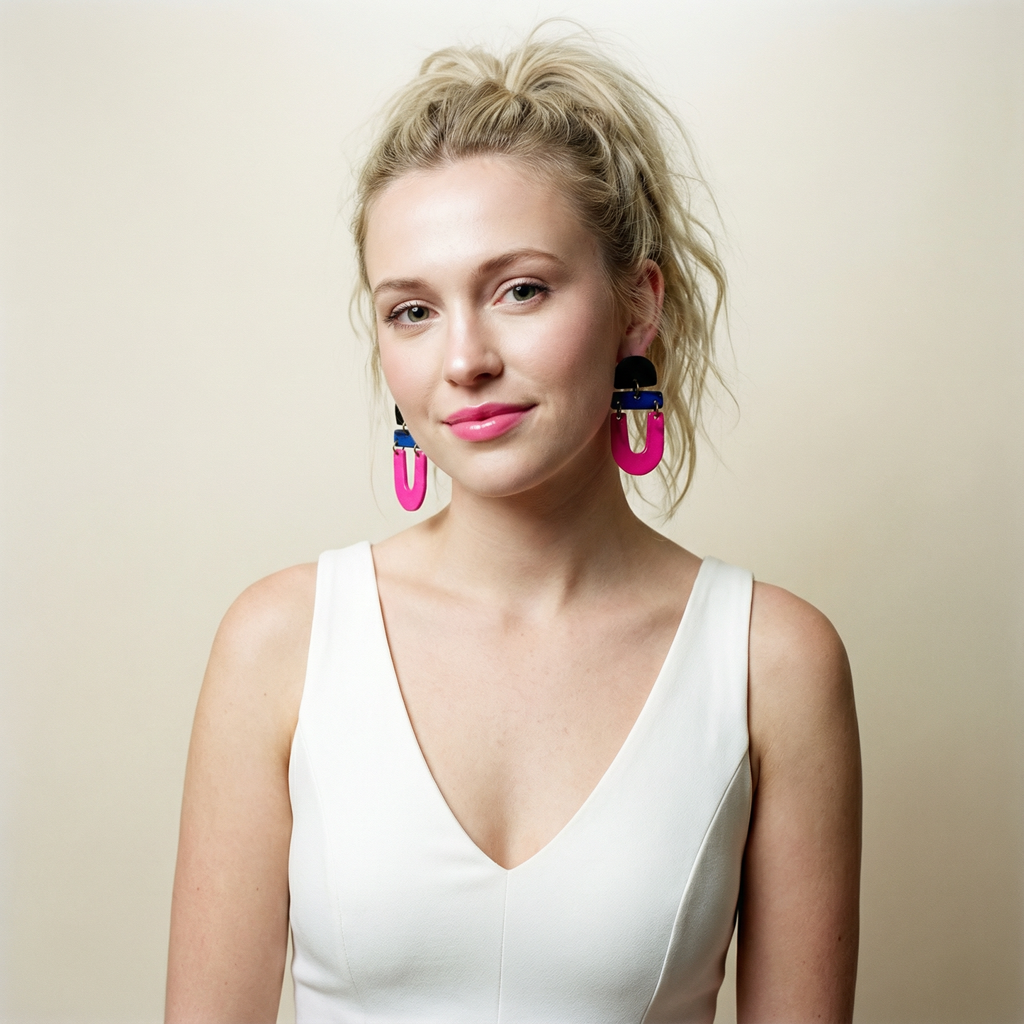 Woman wearing large colorful earrings against a plain background