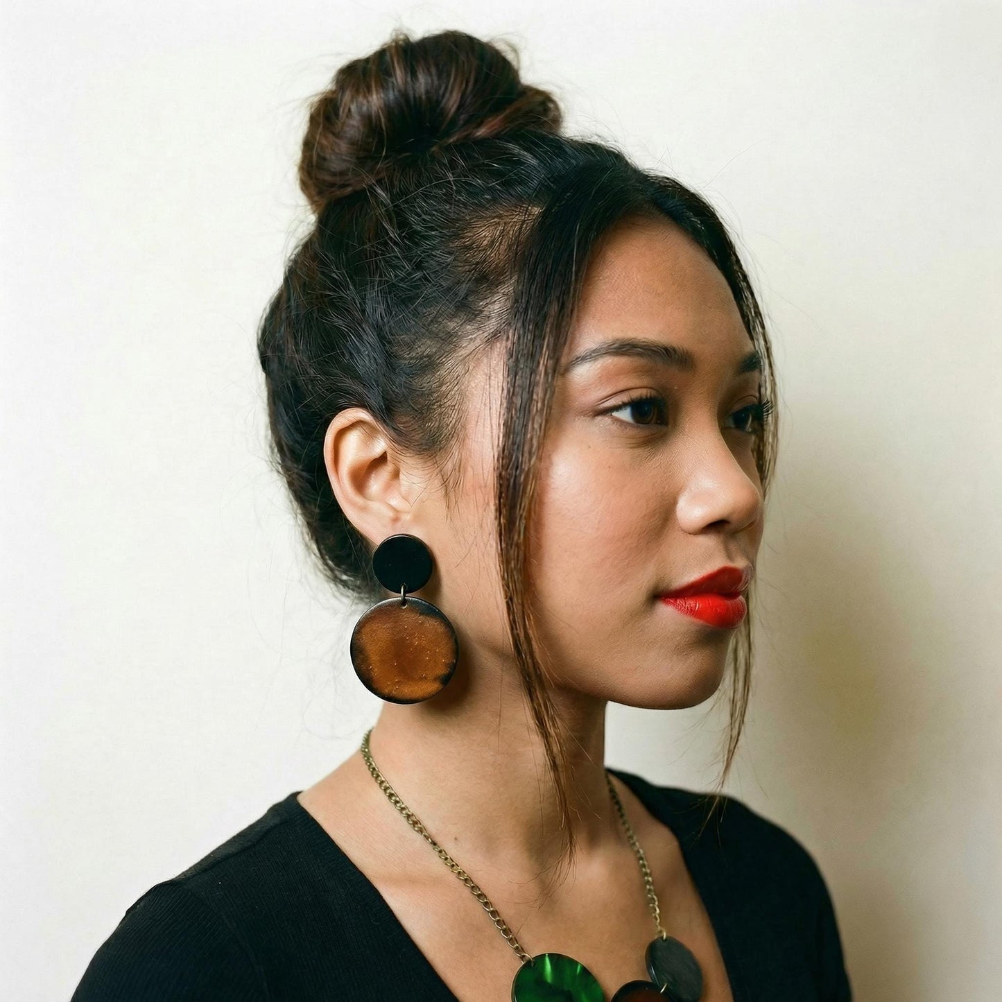 Woman wearing large wooden earrings with a neutral background