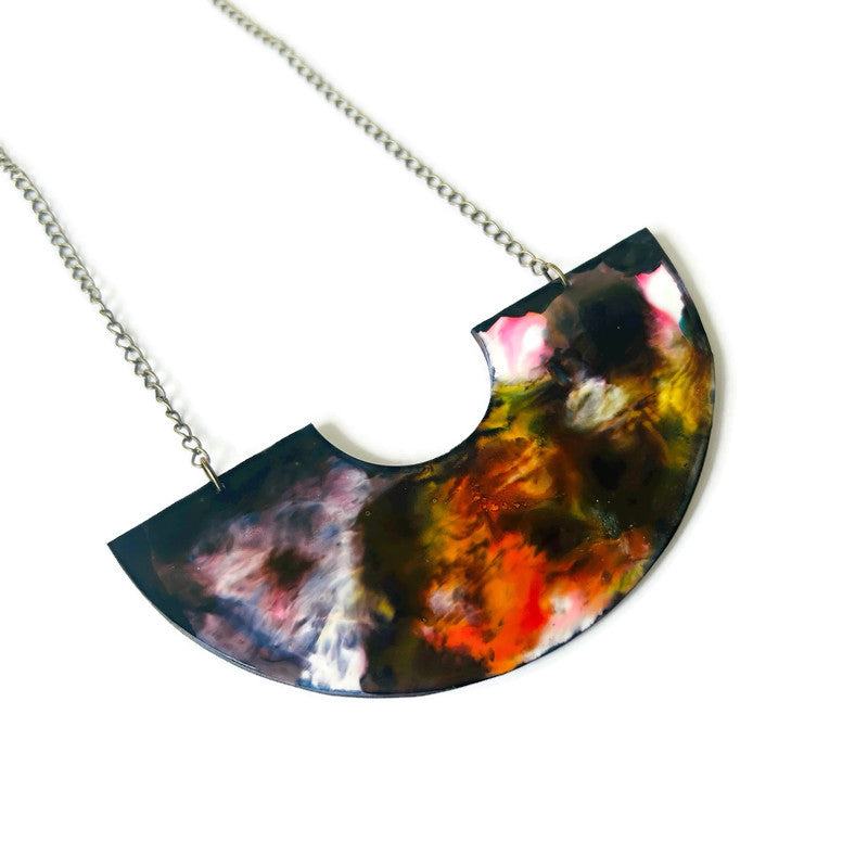 Colorful half-circle pendant on a chain against a white background