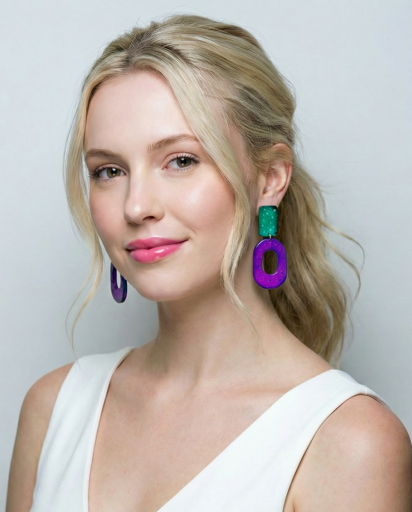 Woman wearing colorful earrings against a plain background