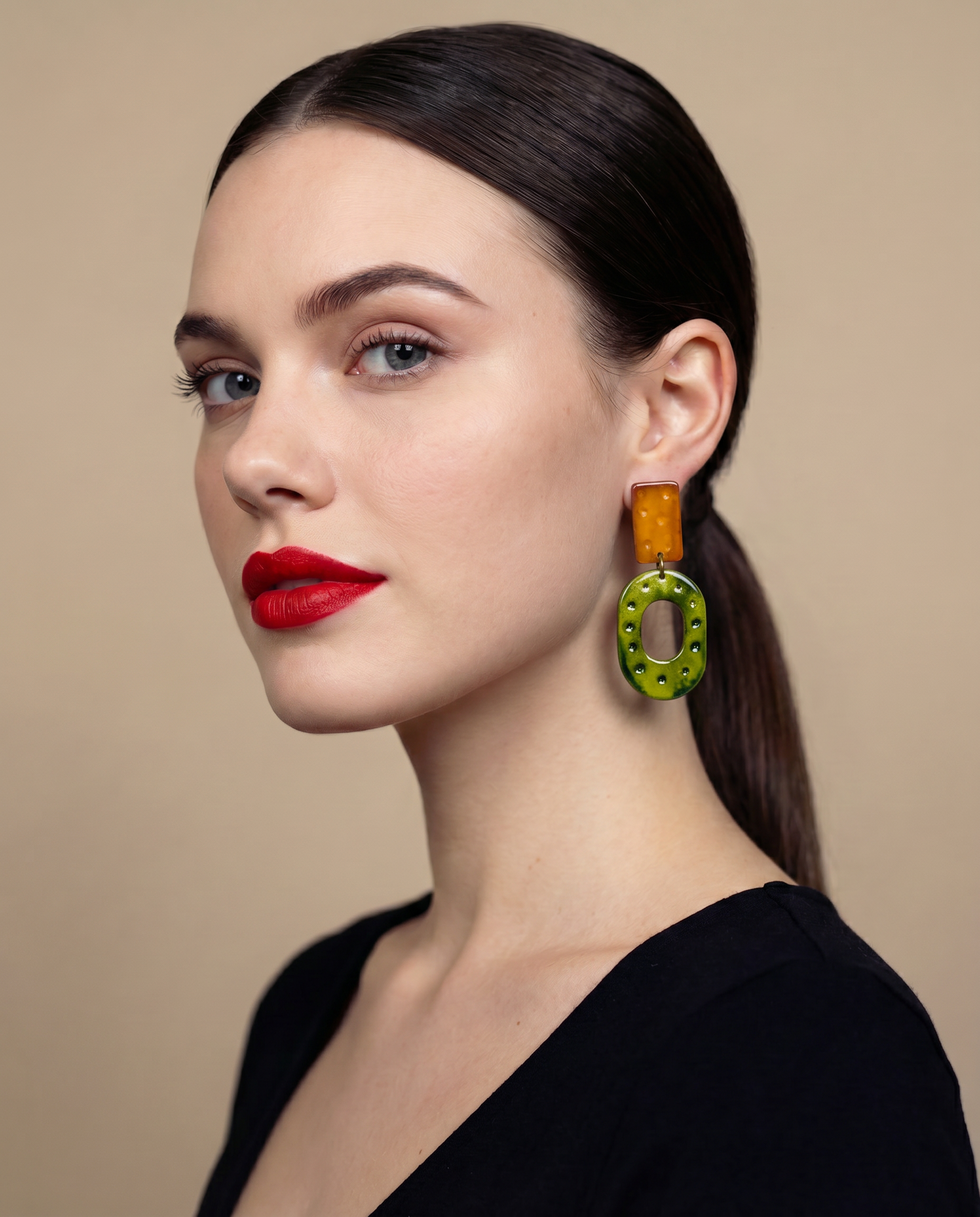 Woman wearing brown and green earrings with a beige background