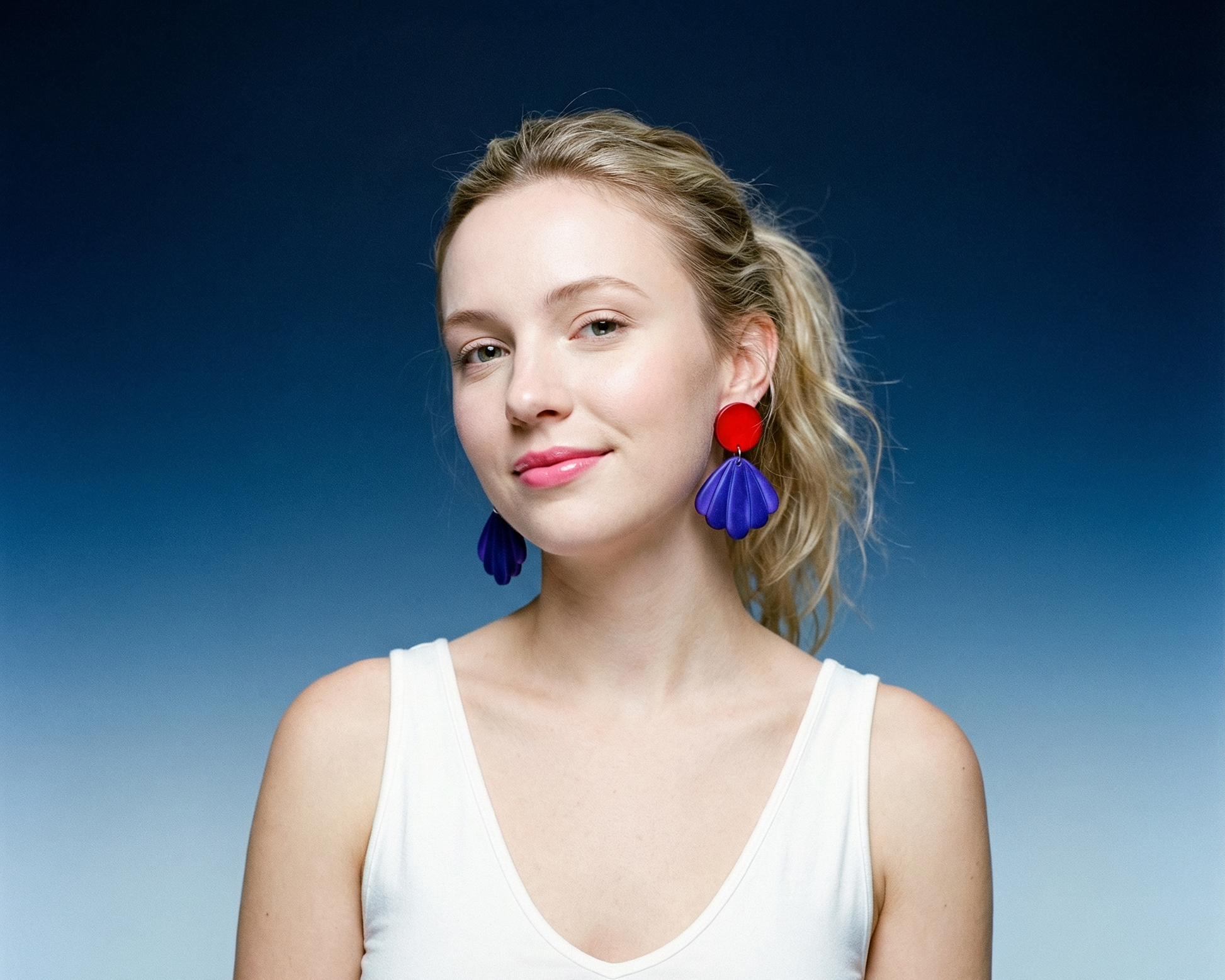 Woman wearing colorful earrings against a gradient blue background