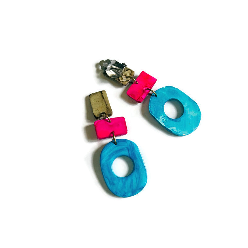 Colorful earrings with blue and pink circular designs on a white background