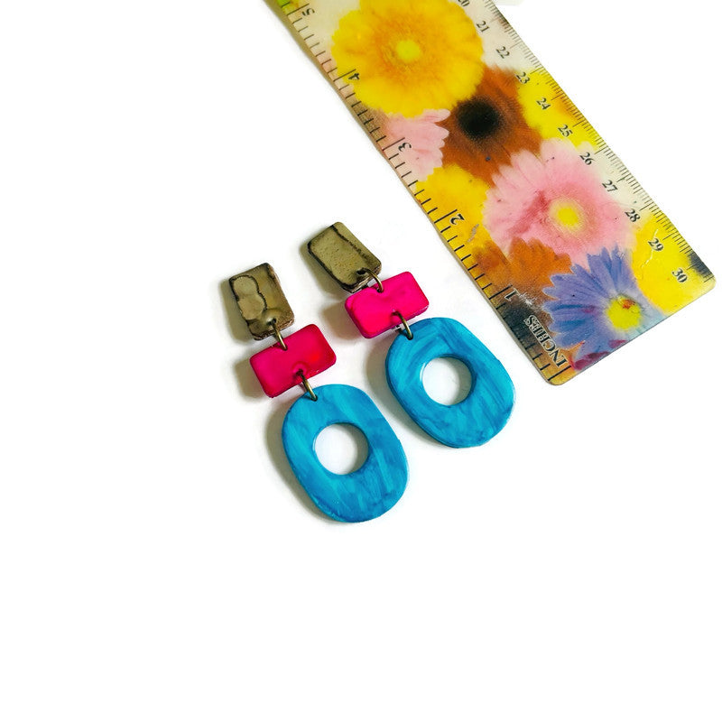 Colorful earrings with a ruler for scale on a floral-patterned background