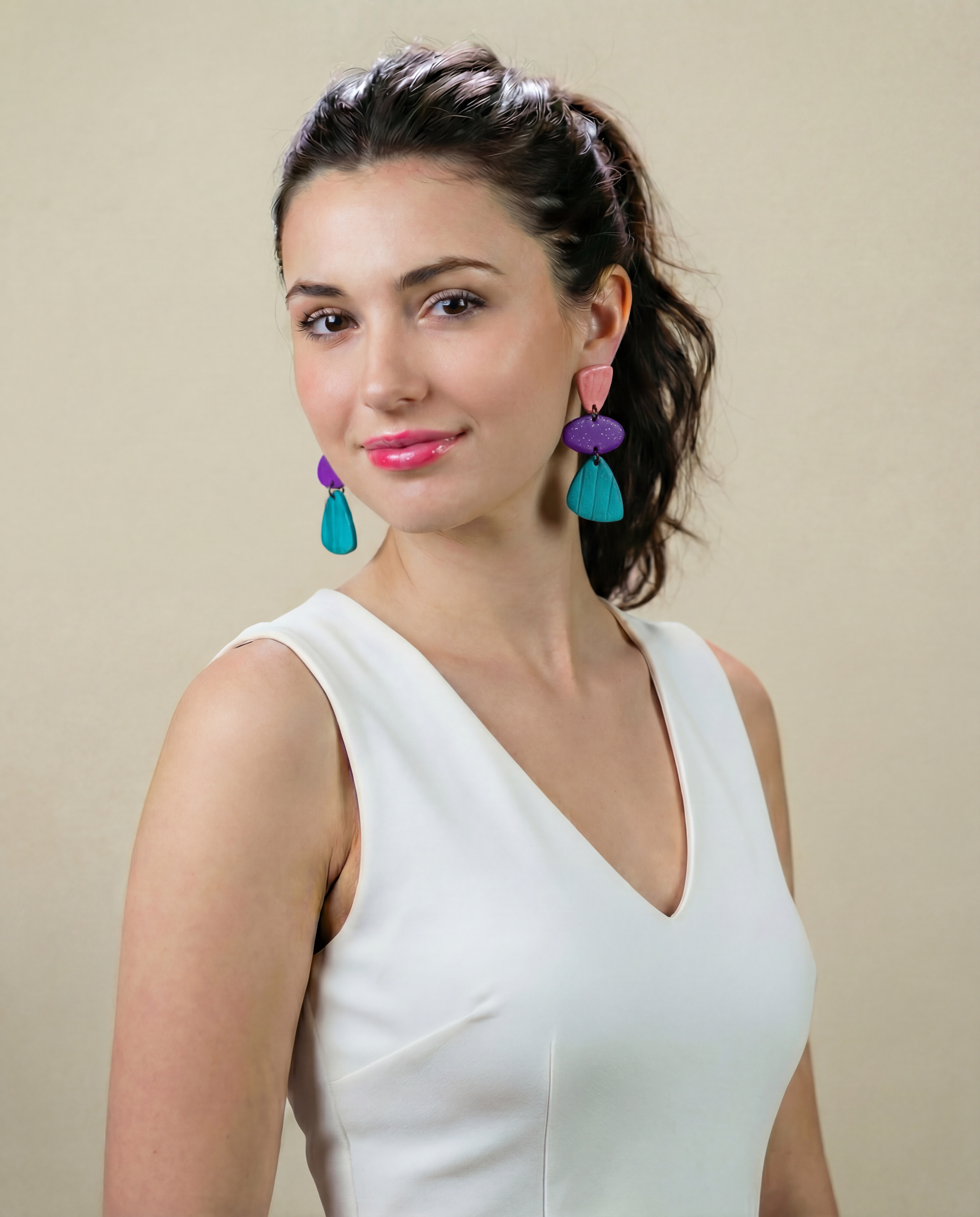 Woman wearing colorful earrings against a beige background