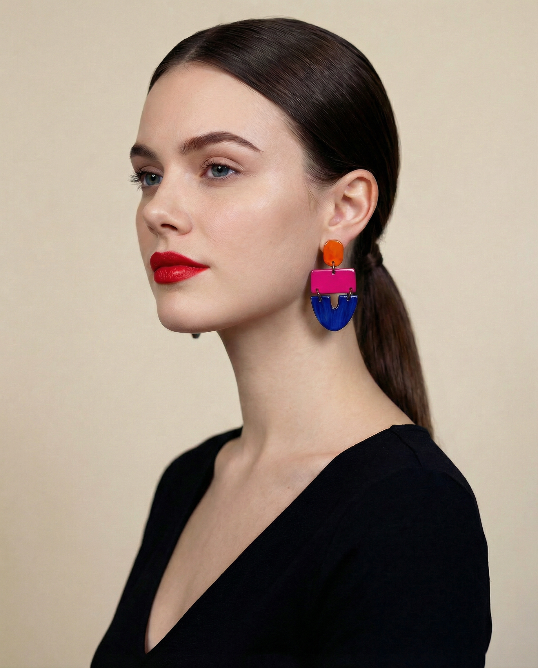 Woman wearing colorful earrings with a neutral background