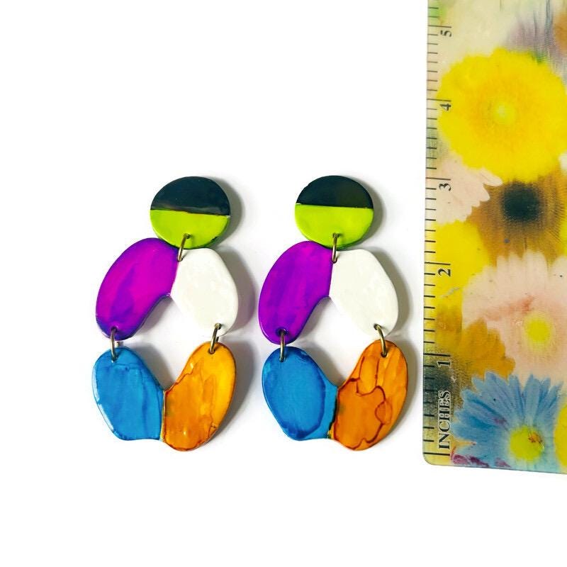 Colorful earrings with a white background and floral ruler for scale