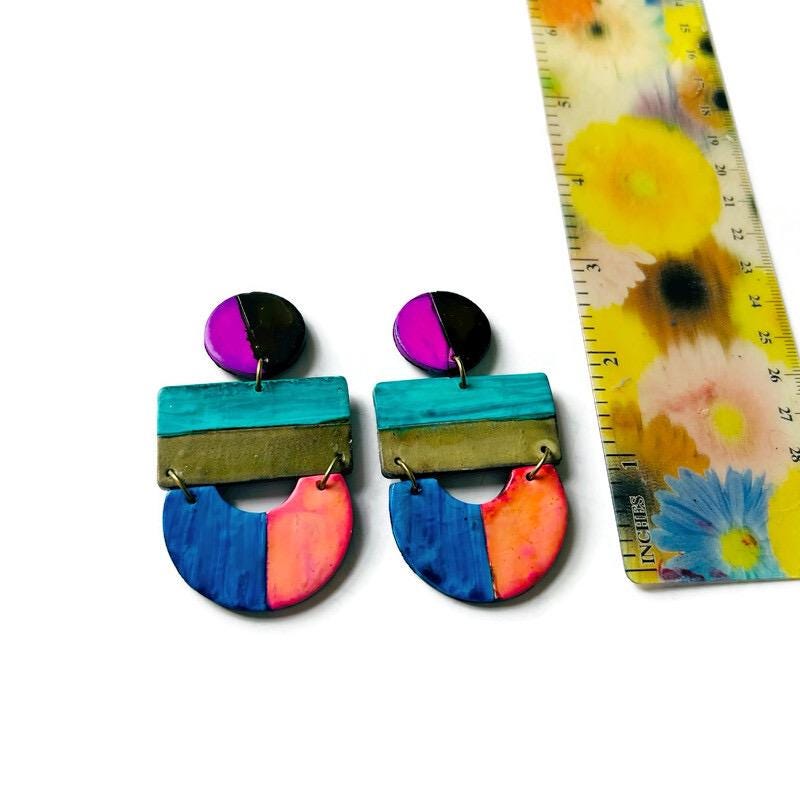 Colorful geometric earrings with a floral-patterned ruler on a white background