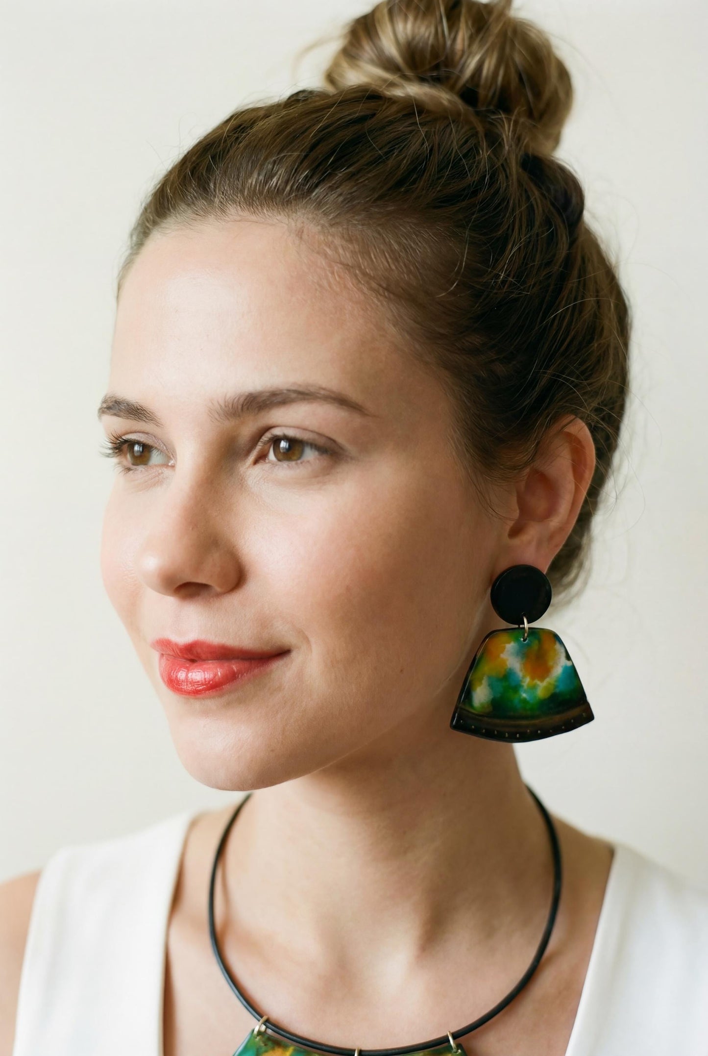 Woman wearing colorful earrings against a plain background