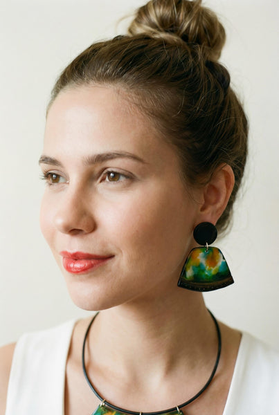 Woman wearing colorful earrings against a plain background