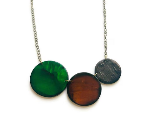 Necklace with three circular pendants in green, brown, and black on a white background