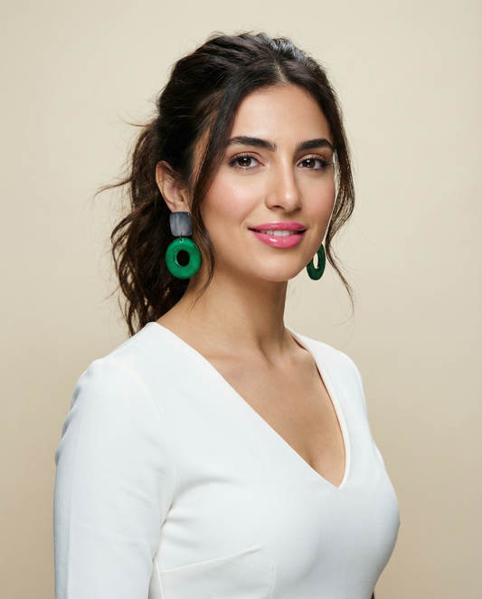 Woman wearing green earrings against a beige background