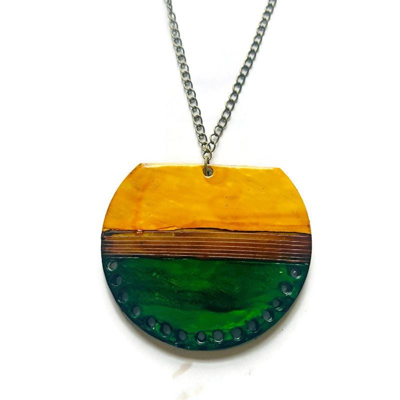 Necklace with a round pendant featuring a yellow top and green bottom on a white background