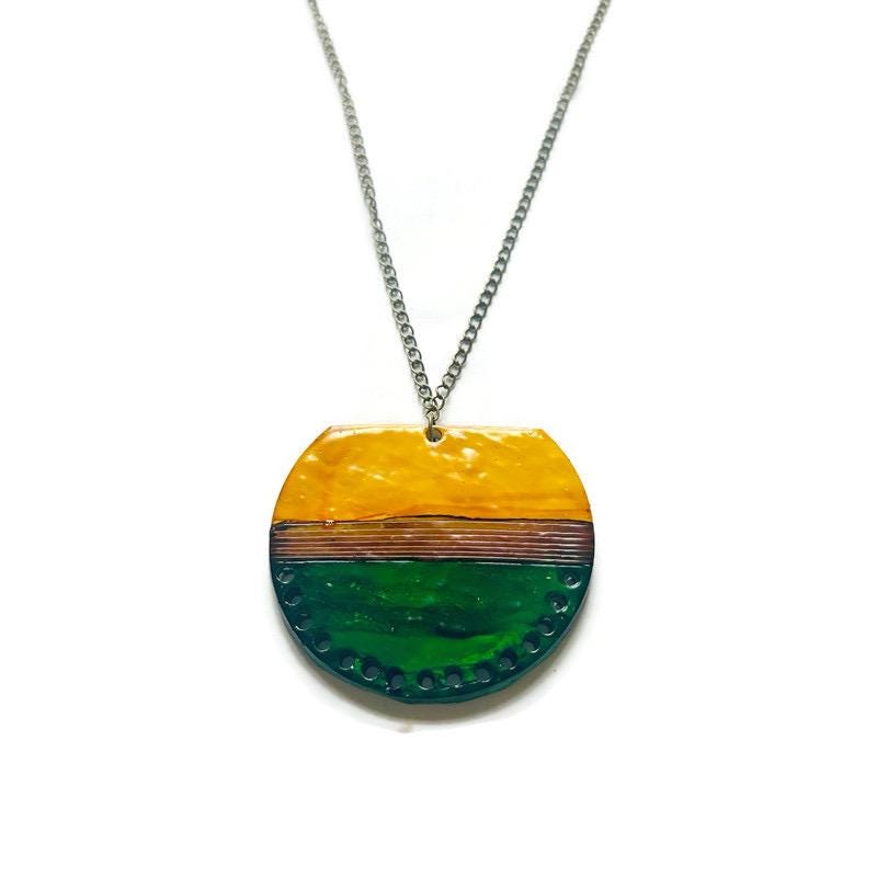 Necklace with a round pendant featuring yellow and green colors on a white background