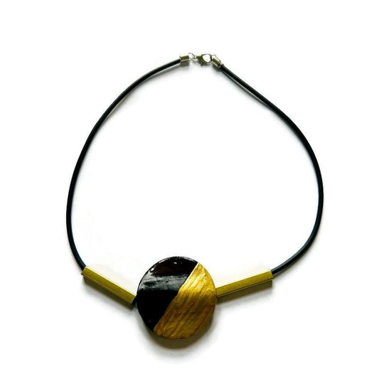 Black cord necklace with oval clay bead and brass bar accents
