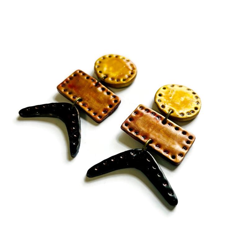Geometric drop earrings with gold-yellow circles, copper rectangles, and black curved points.