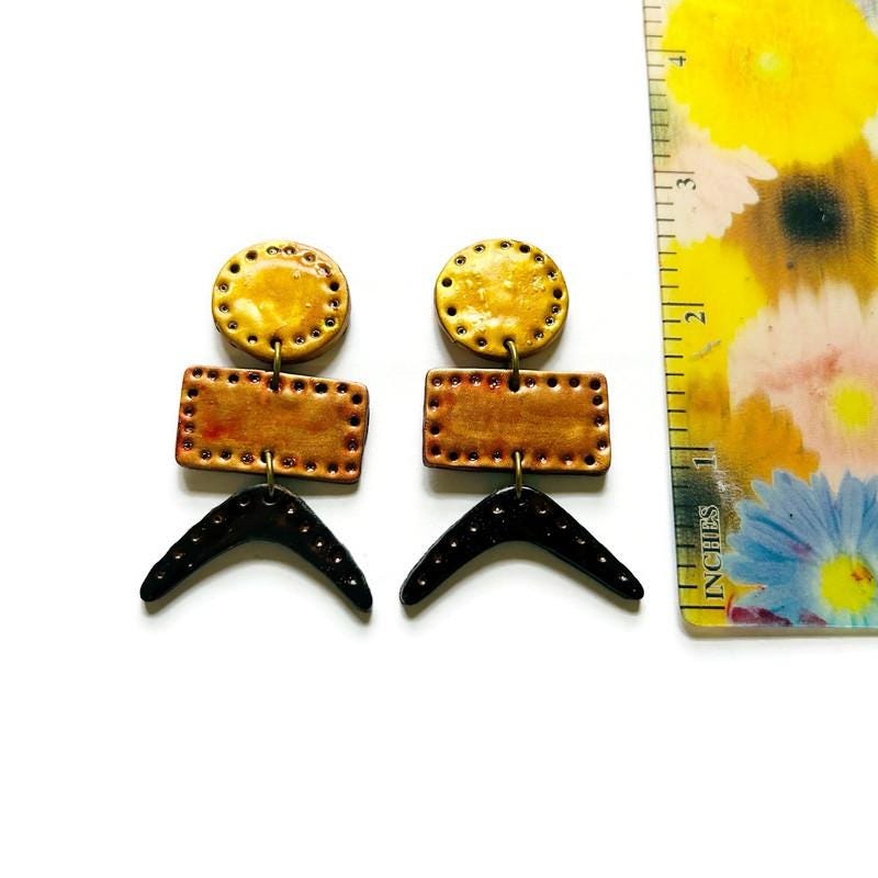 Geometric drop earrings shown with ruler for size: yellow circles, copper rectangles, black tails.