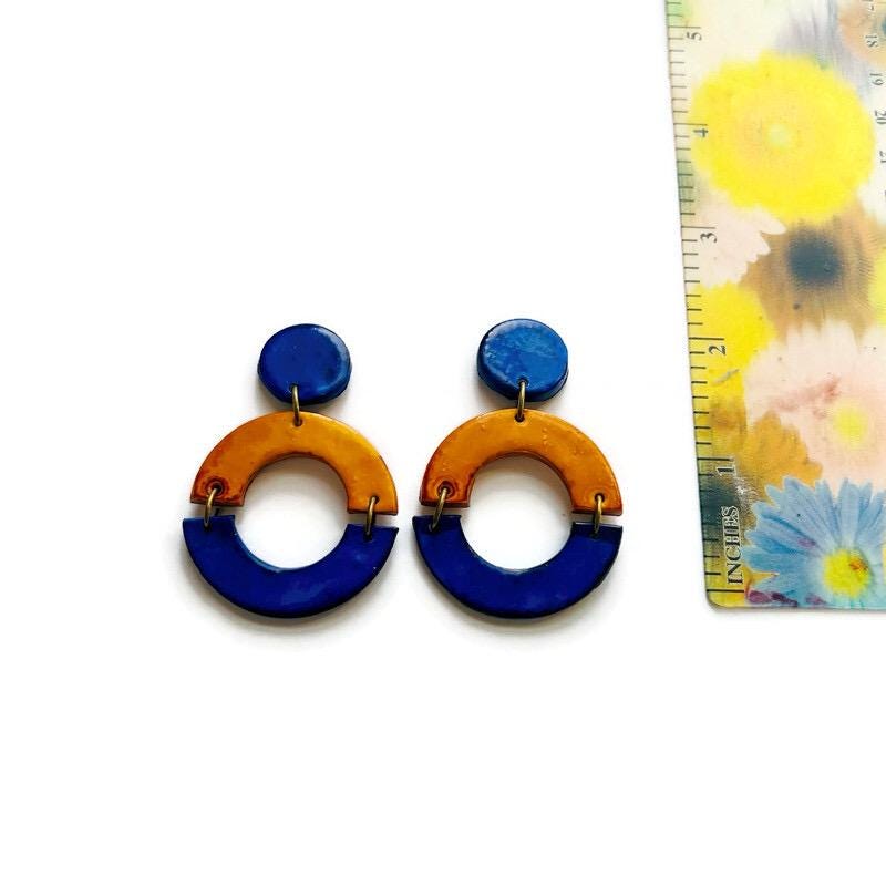 Colorful hoop earrings with a ruler for scale on a white background