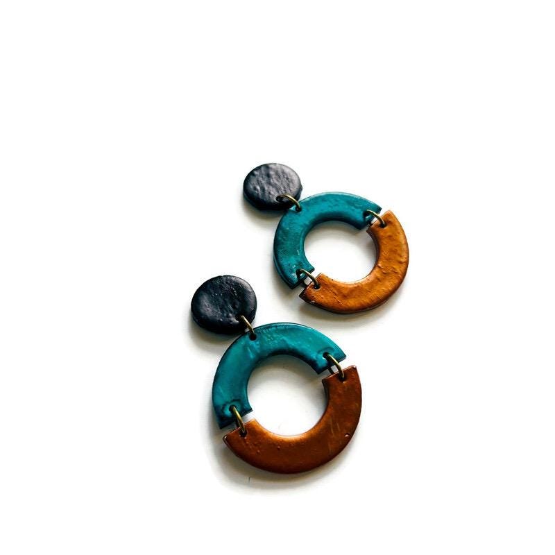 Pair of earrings with teal and brown circular designs on a white background