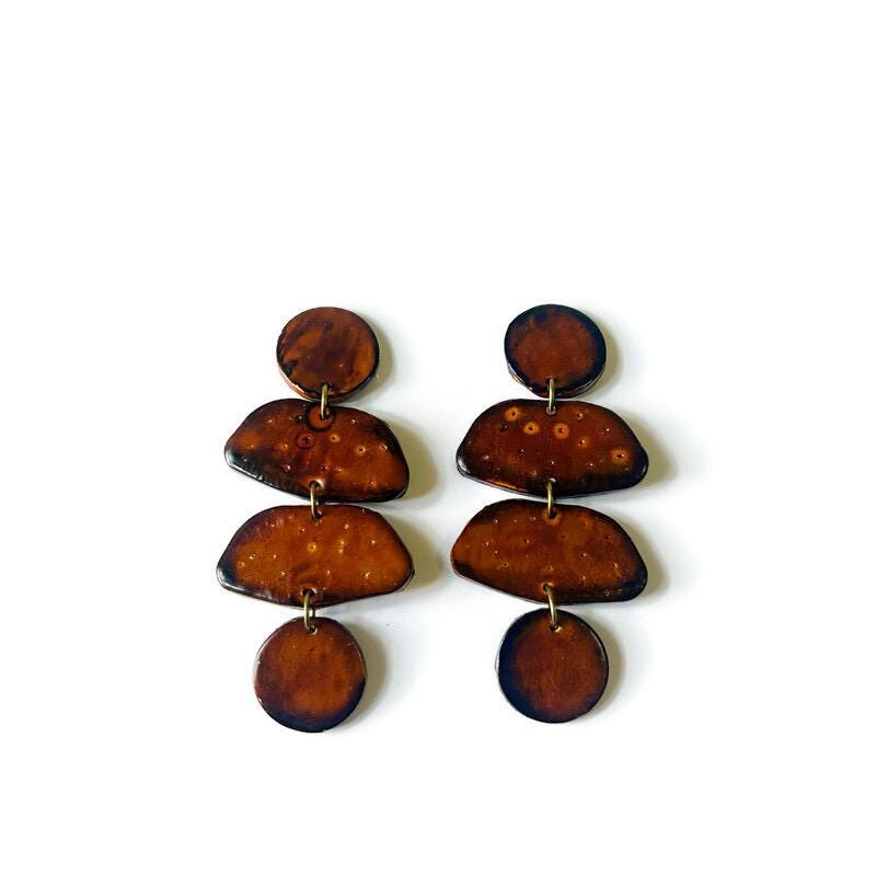 Pair of brown earrings with circular designs on a white background