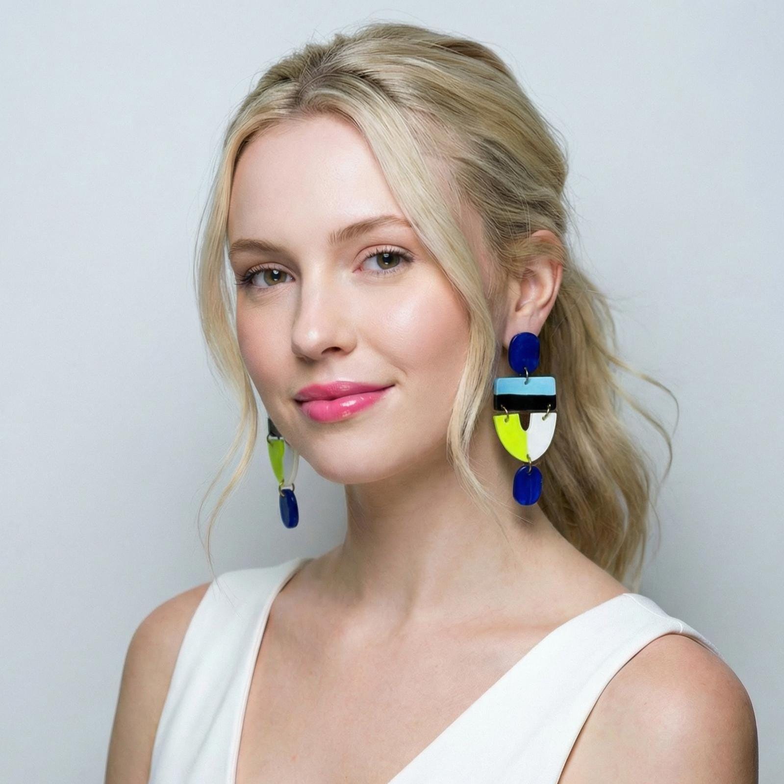 Woman wearing colorful earrings against a plain background