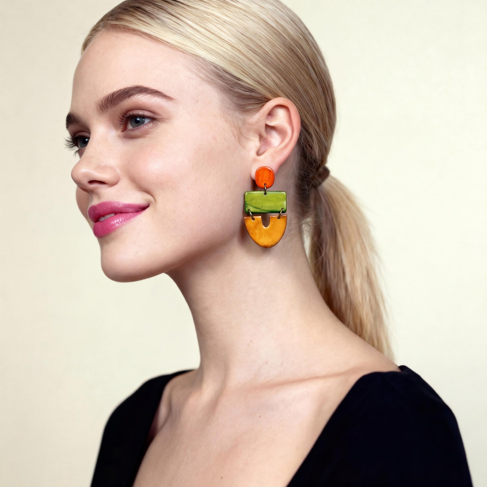 Woman wearing colorful earrings against a plain background