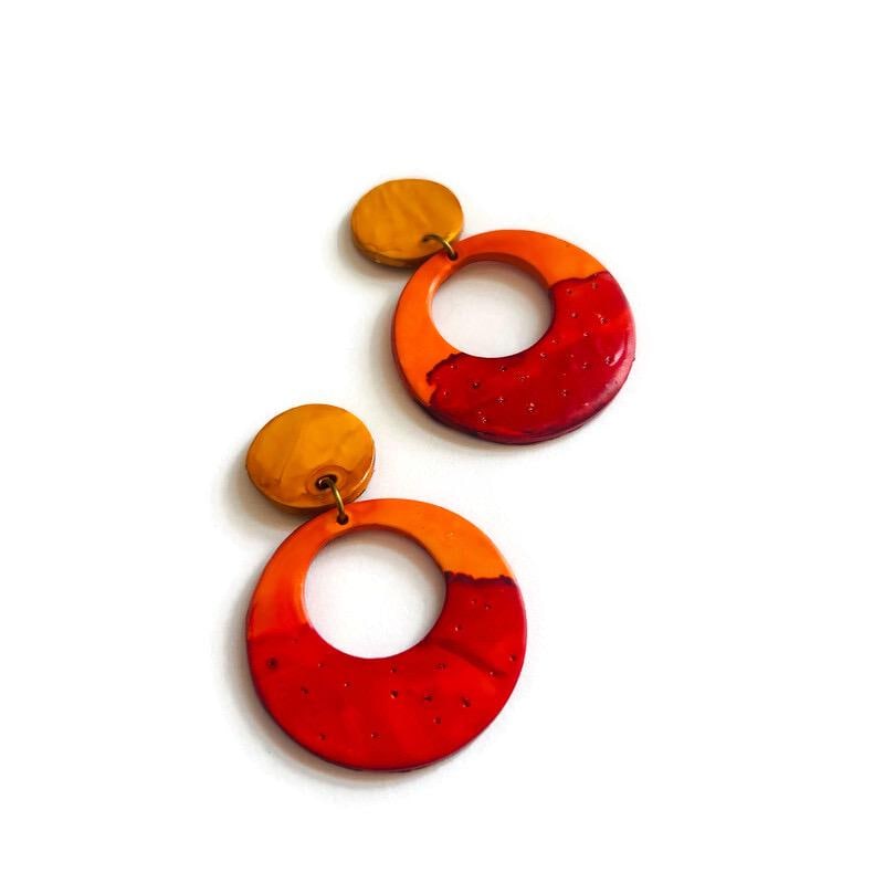 Pair of orange-red ombre polymer clay hoop earrings with gold posts and speckled texture