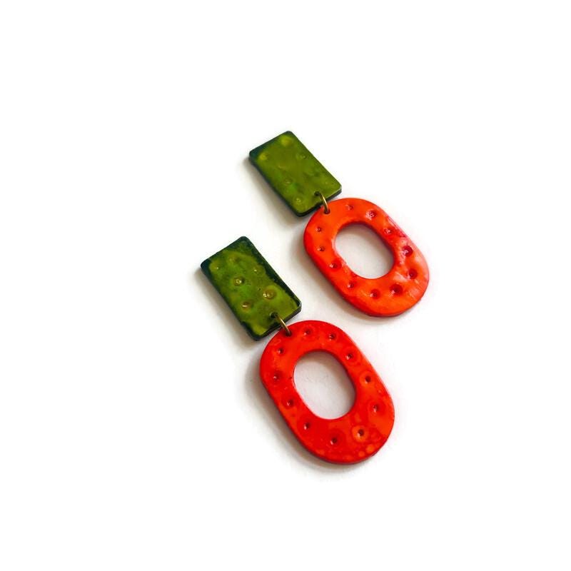 Pair of green and orange earrings on a white background