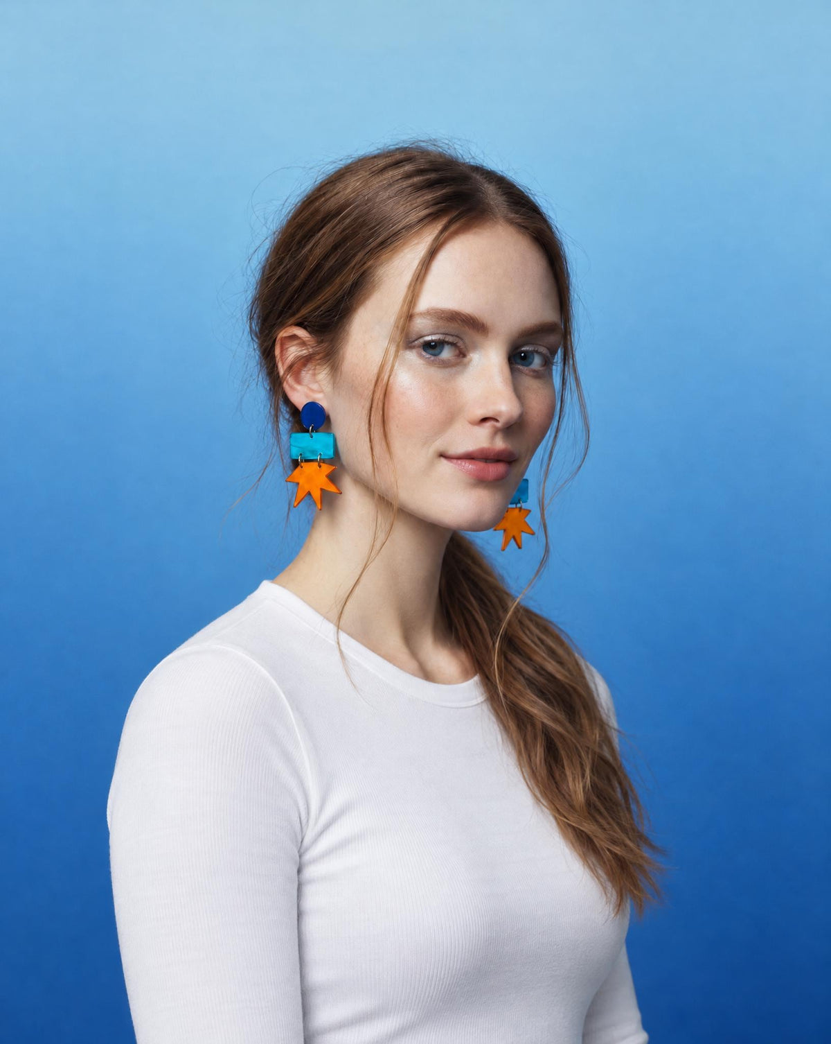 Geometric star drop earrings with blue round tops and orange star charms