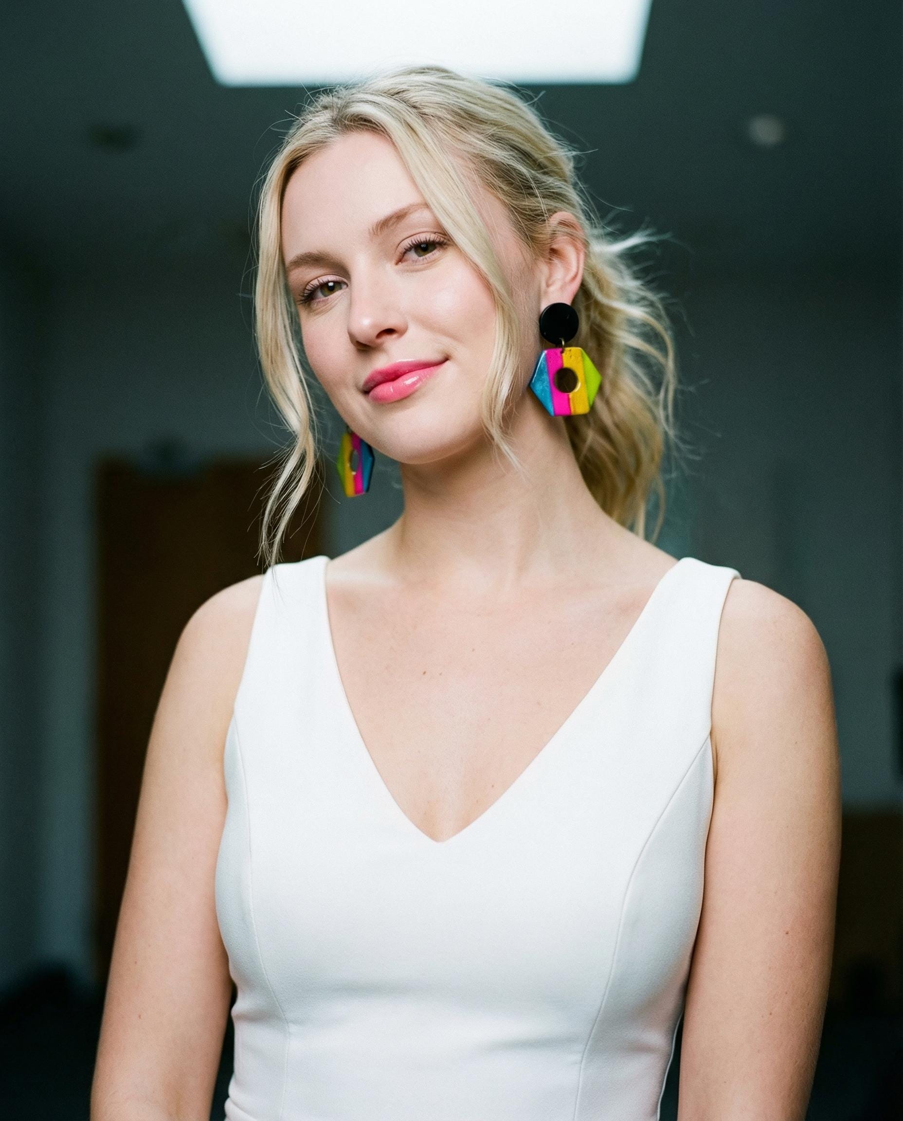 Woman wearing colorful earrings in a blurred indoor setting