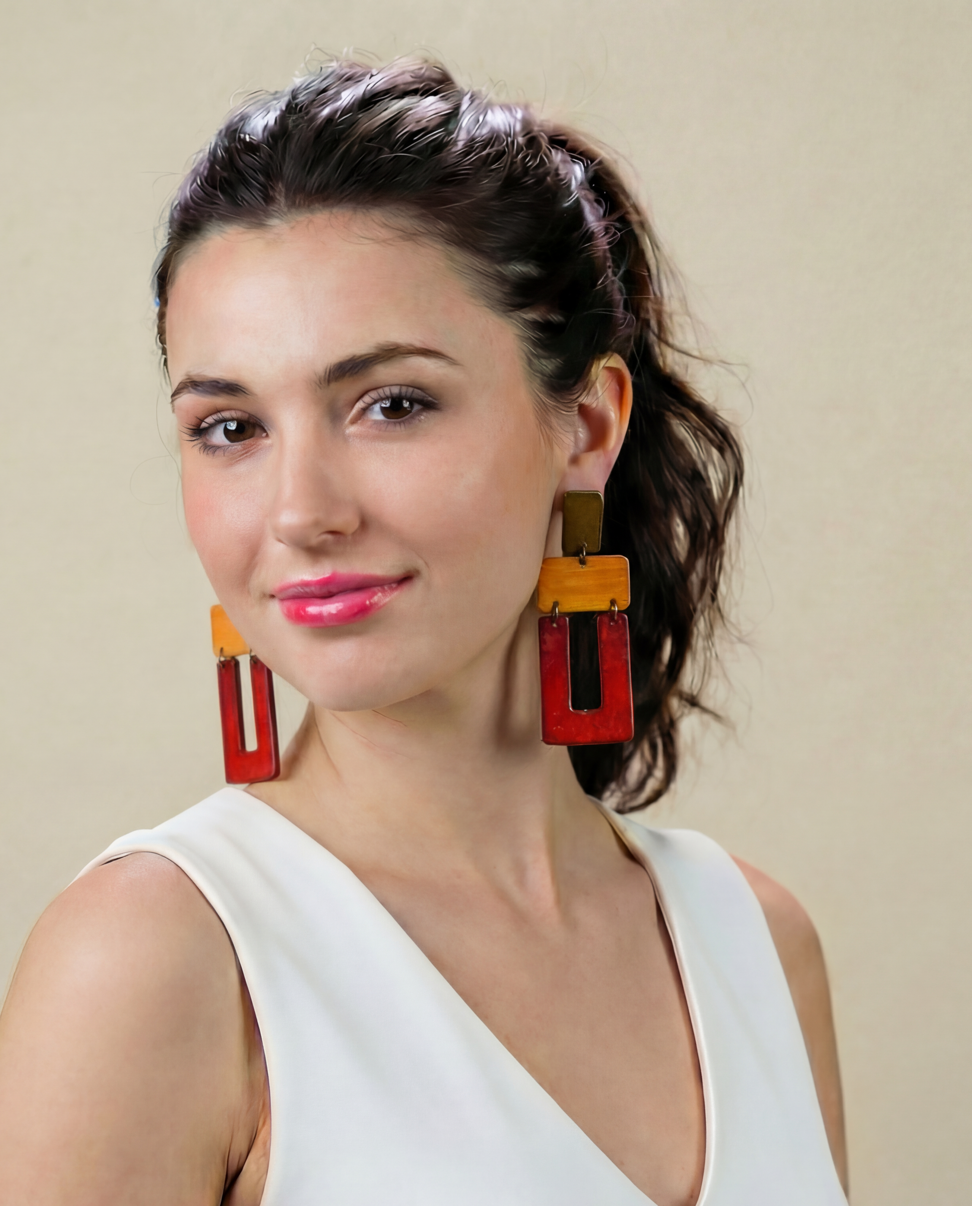 Woman wearing colorful earrings against a beige background