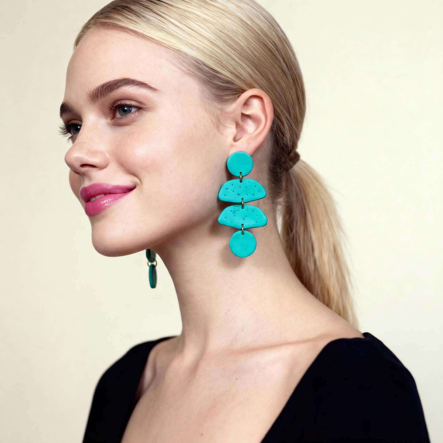 Woman wearing turquoise earrings against a beige background