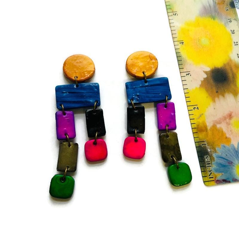 Colorful earrings with a ruler for scale on a floral background