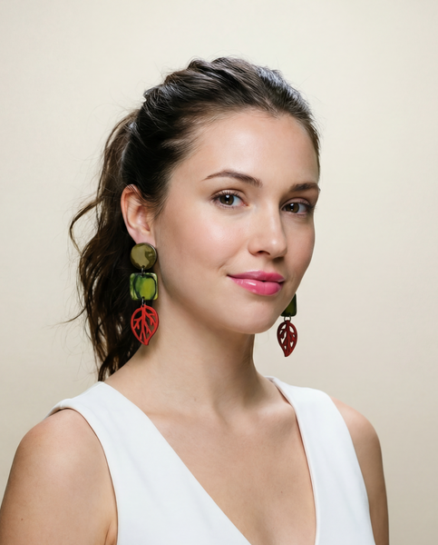Woman wearing a white sleeveless top with colorful earrings against a beige background